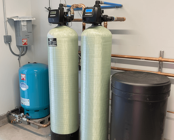 A whole-home water softener system installed in a garage